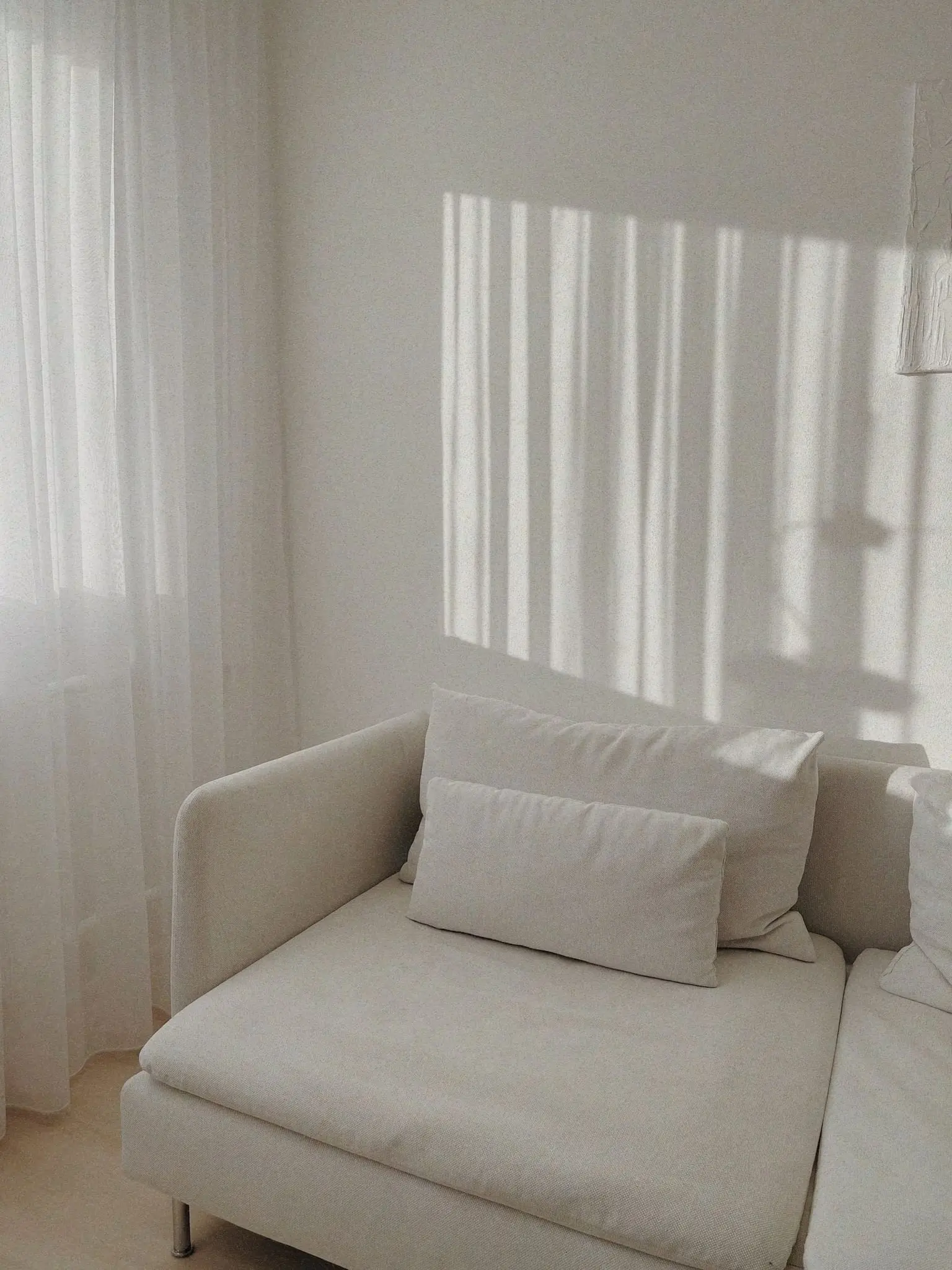 Een lichte woonkamer met een witte bank